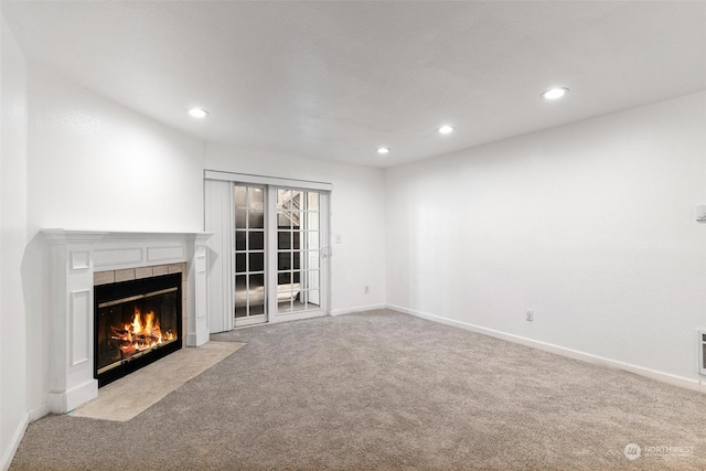 unfurnished living room with a tiled fireplace and light carpet