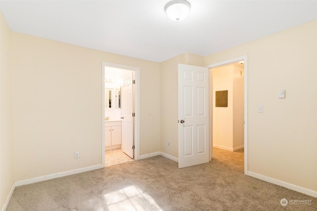 unfurnished bedroom featuring ensuite bath and light colored carpet