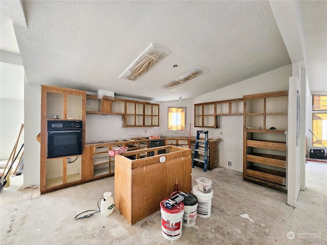 kitchen featuring lofted ceiling, oven, dishwashing machine, and a textured ceiling