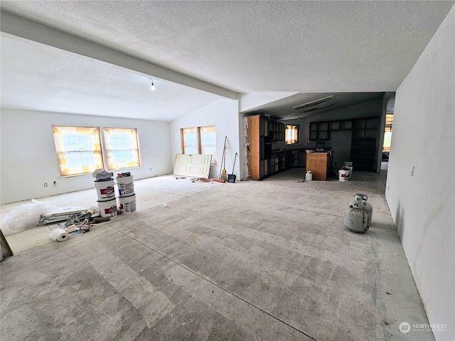 unfurnished living room with vaulted ceiling with beams and a textured ceiling