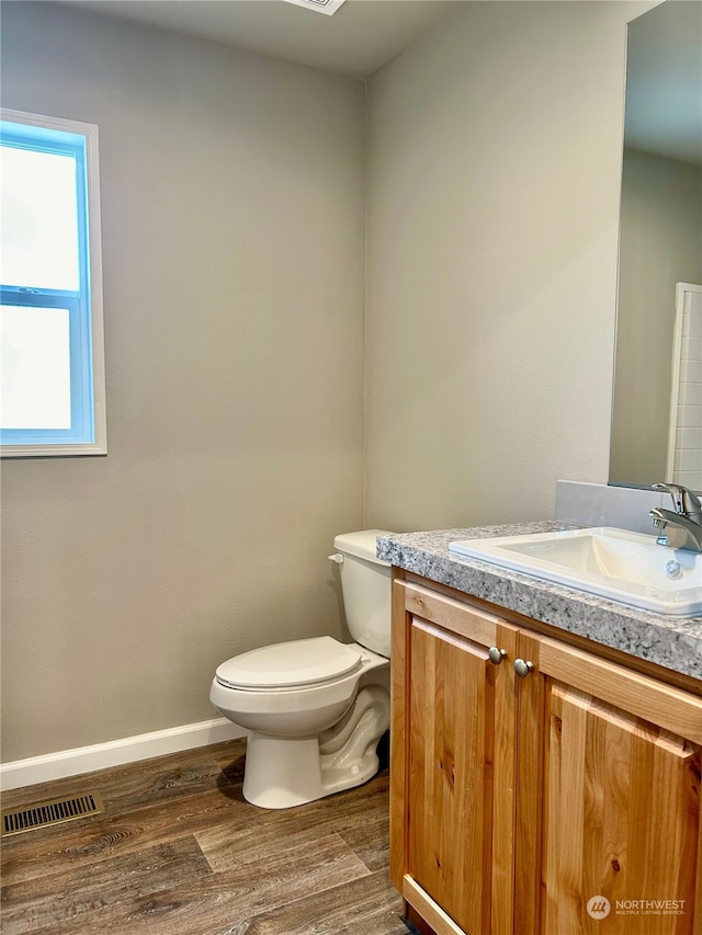 bathroom with hardwood / wood-style floors, vanity, and toilet