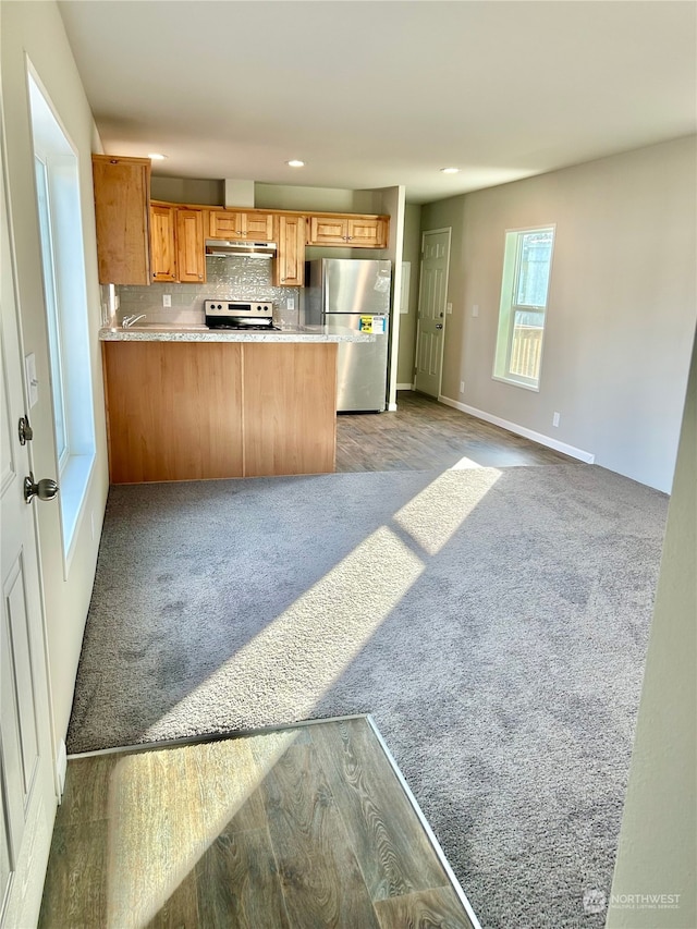 kitchen with stove, stainless steel fridge, carpet flooring, kitchen peninsula, and tasteful backsplash