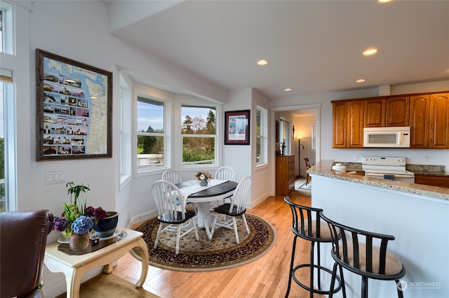 kitchen featuring light stone countertops, light hardwood / wood-style floors, and white appliances