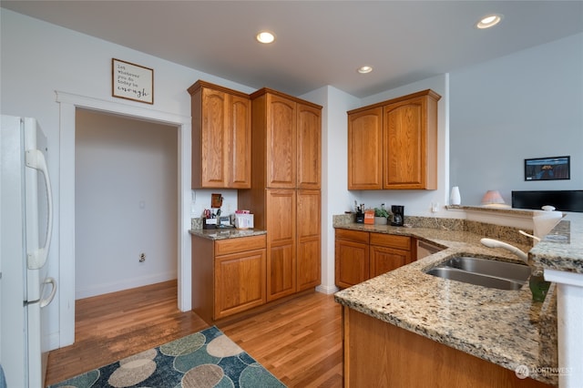 kitchen featuring light stone countertops, light hardwood / wood-style flooring, white fridge, and kitchen peninsula