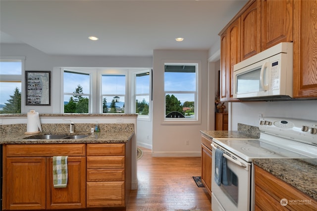 kitchen with light stone countertops, sink, white appliances, and light hardwood / wood-style flooring