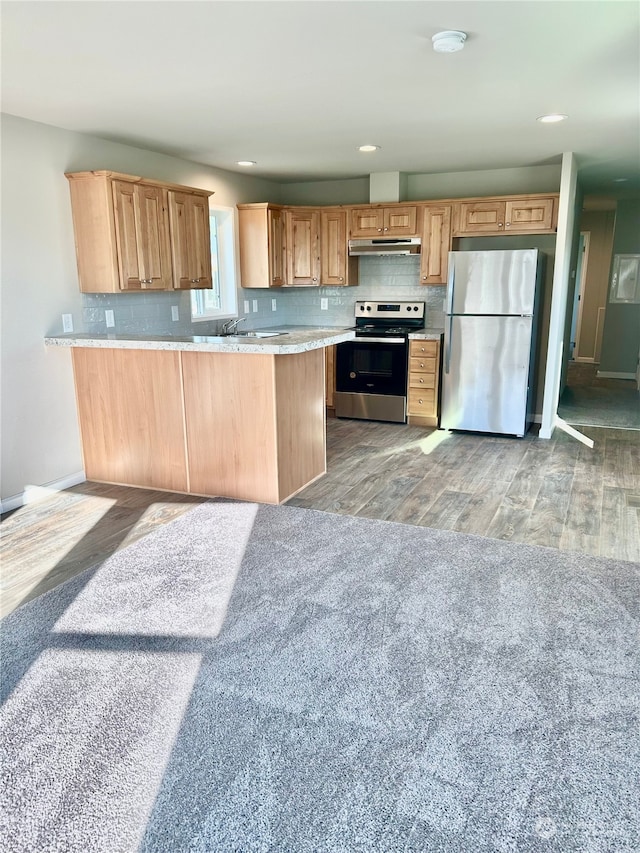 kitchen featuring light brown cabinetry, light wood-type flooring, kitchen peninsula, and appliances with stainless steel finishes