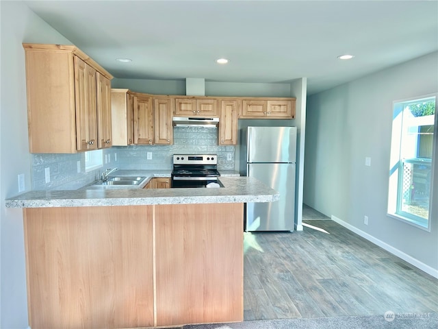 kitchen with sink, kitchen peninsula, backsplash, stainless steel appliances, and light hardwood / wood-style floors