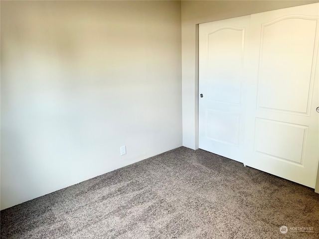 unfurnished room with dark colored carpet