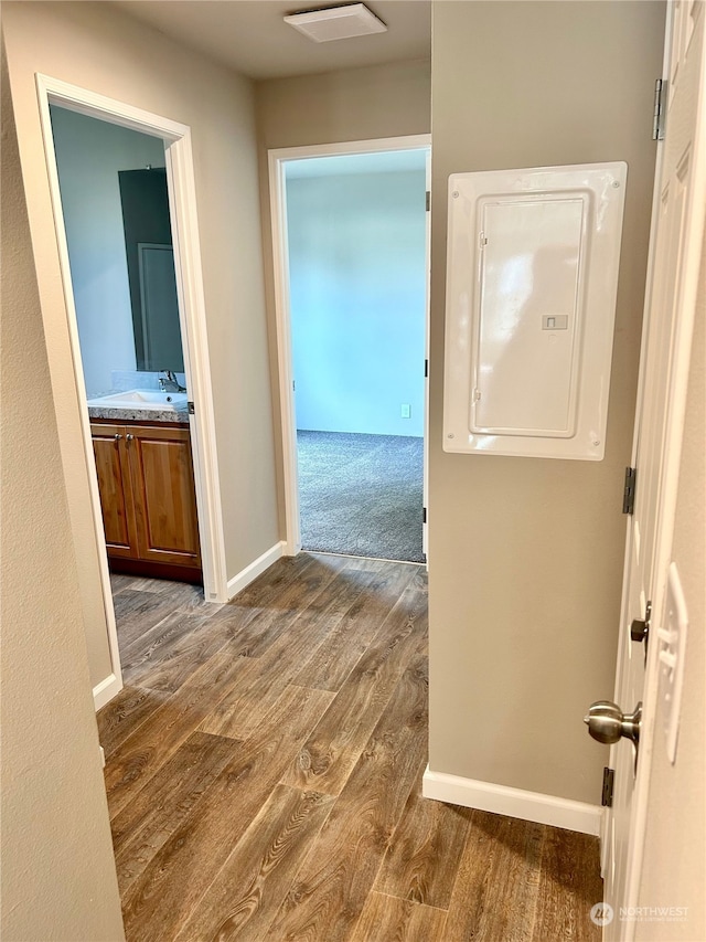 hallway with electric panel, dark wood-type flooring, and sink