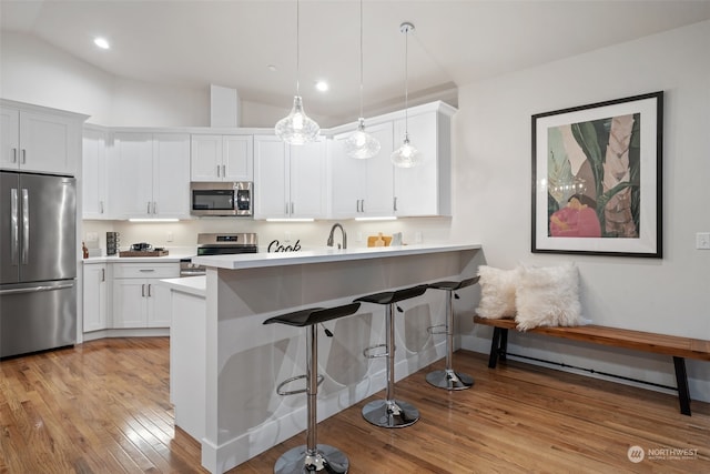 kitchen with kitchen peninsula, hanging light fixtures, stainless steel appliances, lofted ceiling, and white cabinets