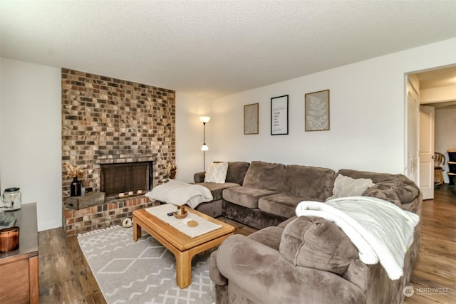 living room with dark hardwood / wood-style flooring, a brick fireplace, and a textured ceiling