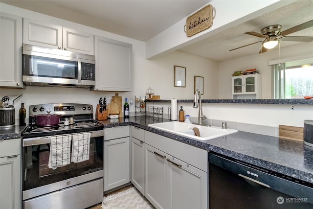 kitchen featuring kitchen peninsula, stainless steel appliances, white cabinetry, ceiling fan, and sink