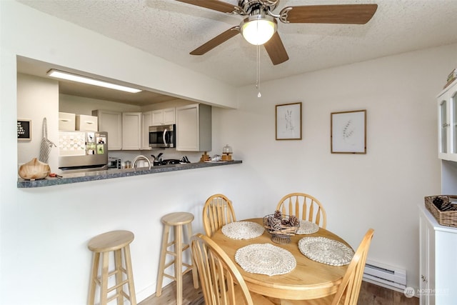 dining room featuring a textured ceiling, dark wood-type flooring, and a baseboard radiator