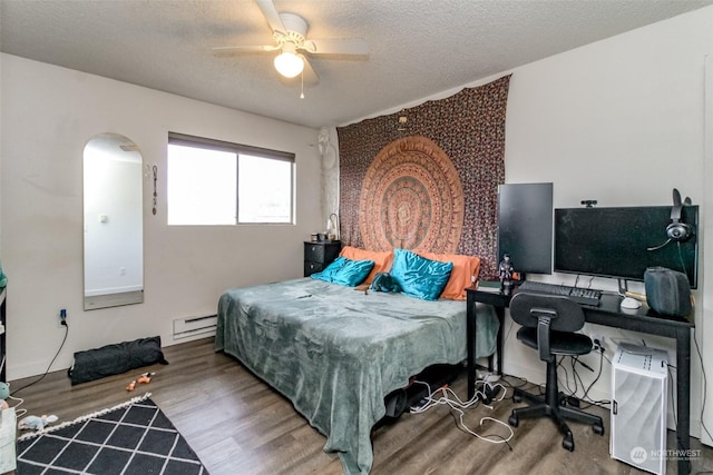 bedroom with ceiling fan, baseboard heating, a textured ceiling, and hardwood / wood-style flooring