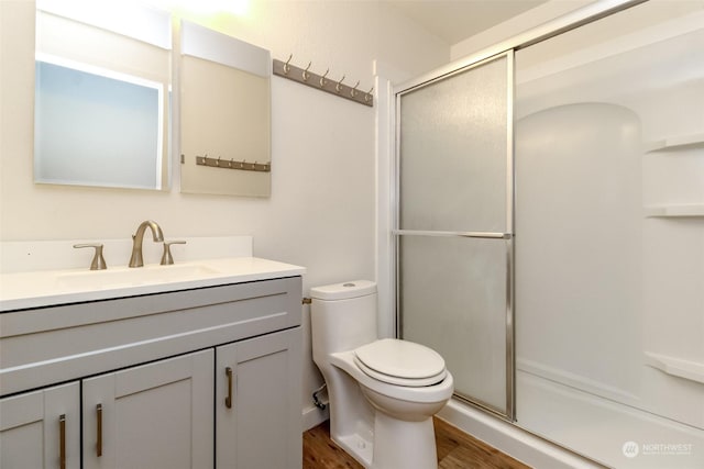 bathroom with a shower with door, toilet, vanity, and hardwood / wood-style flooring