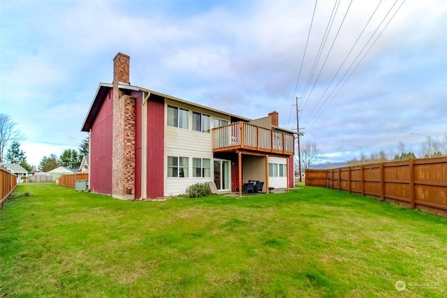 back of property with a lawn and a deck