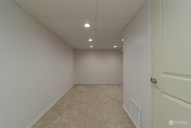 carpeted spare room featuring a drop ceiling