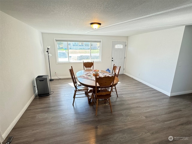 dining area with a textured ceiling and dark hardwood / wood-style flooring