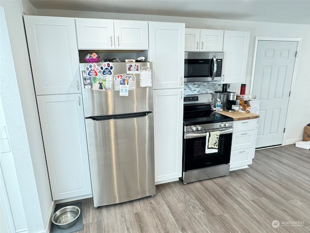 kitchen featuring light wood-type flooring, white cabinetry, appliances with stainless steel finishes, and wooden counters