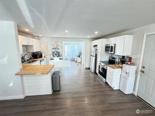 kitchen with dark wood-type flooring, sink, white cabinetry, kitchen peninsula, and appliances with stainless steel finishes