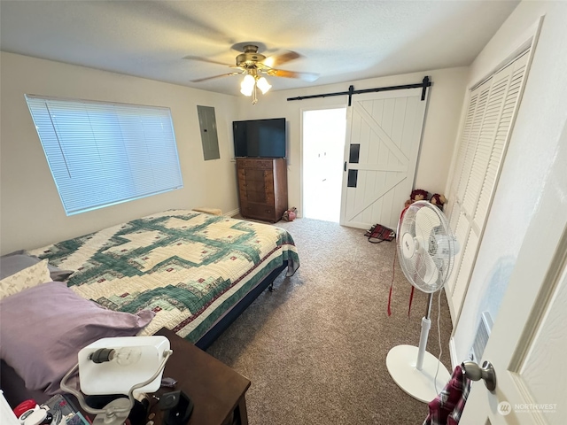 bedroom with a closet, electric panel, carpet flooring, a barn door, and ceiling fan