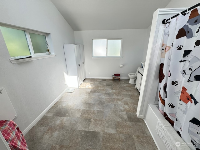 bathroom featuring lofted ceiling, toilet, and shower / bath combination with curtain