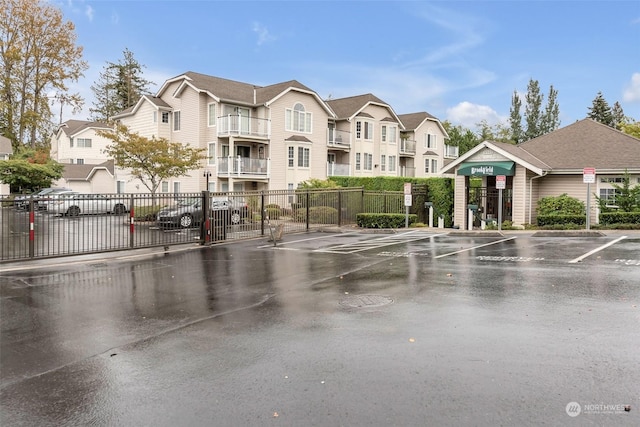 view of community with fence, uncovered parking, and a residential view