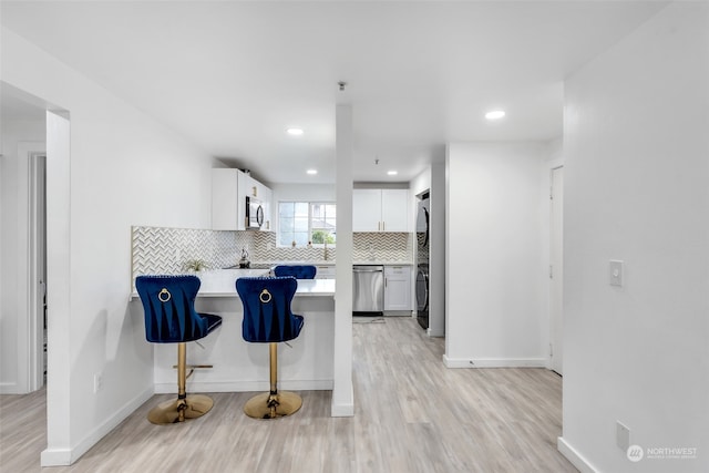 kitchen featuring a kitchen bar, white cabinetry, light hardwood / wood-style floors, and appliances with stainless steel finishes