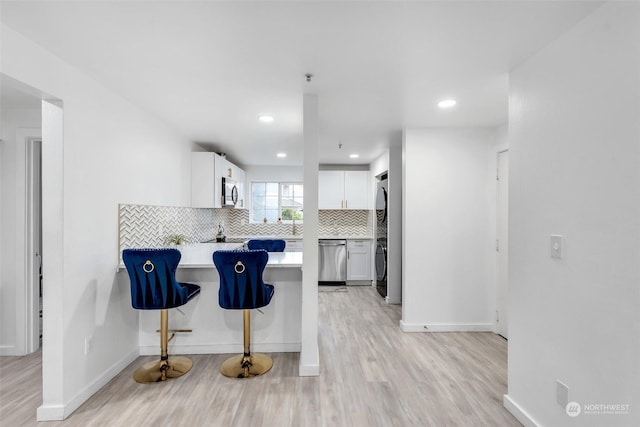 kitchen with appliances with stainless steel finishes, light wood-style floors, white cabinetry, decorative backsplash, and recessed lighting