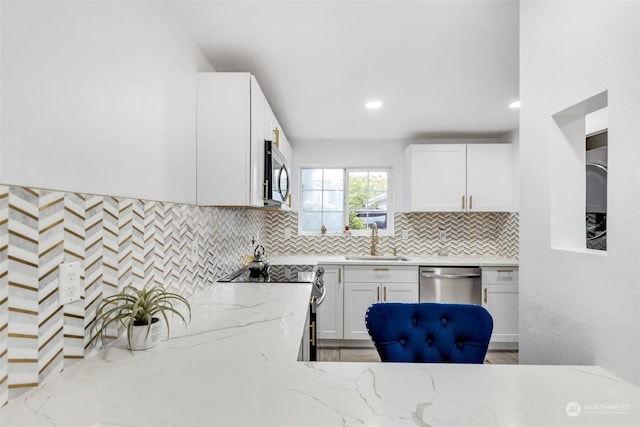 kitchen featuring appliances with stainless steel finishes, a sink, decorative backsplash, white cabinets, and recessed lighting