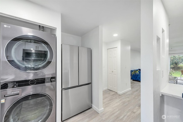 washroom with stacked washer / dryer, light wood-style floors, baseboards, and recessed lighting