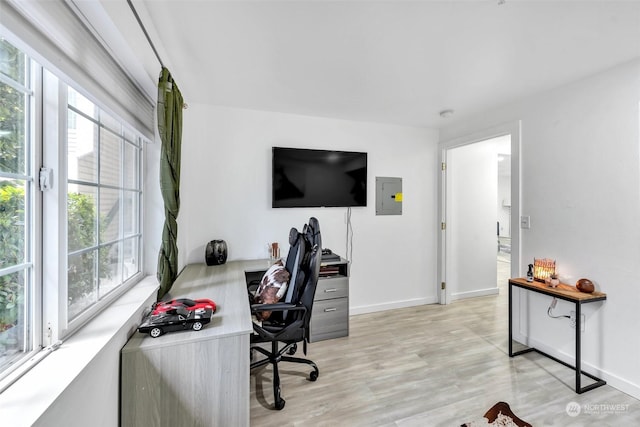 office area with healthy amount of natural light, electric panel, light wood finished floors, and baseboards