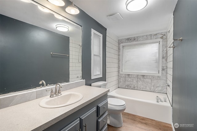 full bathroom featuring tiled shower / bath combo, vanity, toilet, and hardwood / wood-style flooring