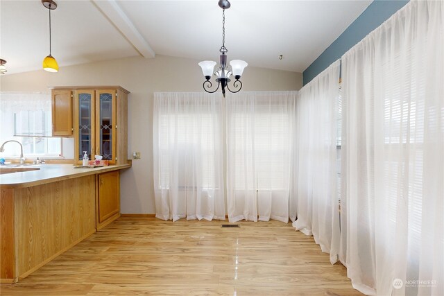 unfurnished dining area with lofted ceiling with beams, sink, a notable chandelier, and light hardwood / wood-style flooring