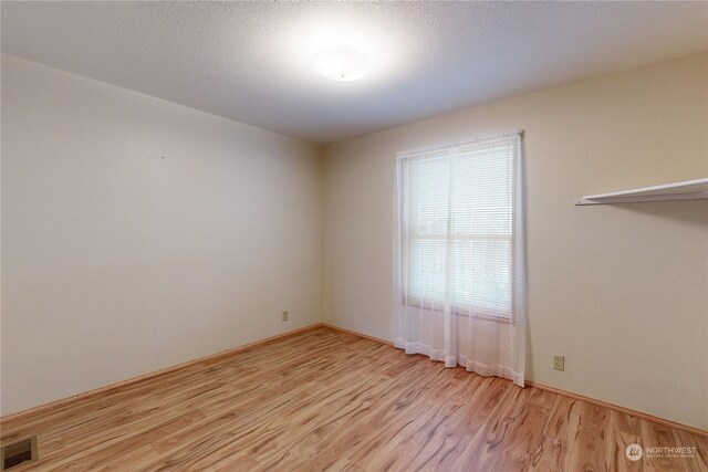 empty room with a textured ceiling and light wood-type flooring