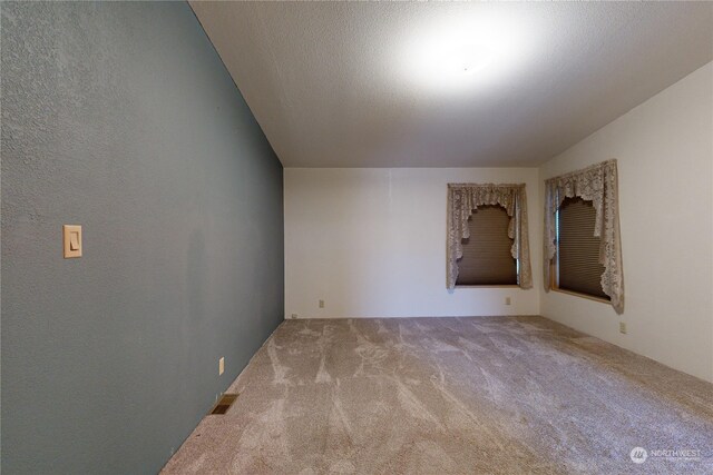 empty room with light carpet and a textured ceiling