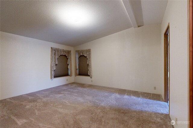 carpeted spare room with lofted ceiling with beams and a textured ceiling