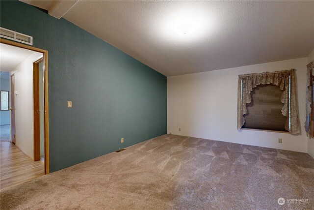 carpeted spare room with lofted ceiling