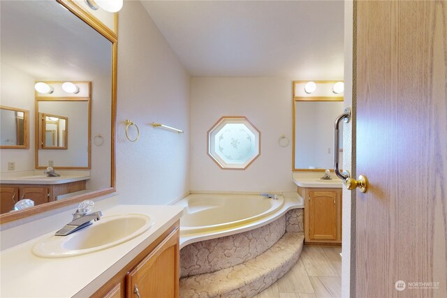 bathroom featuring a relaxing tiled tub and vanity