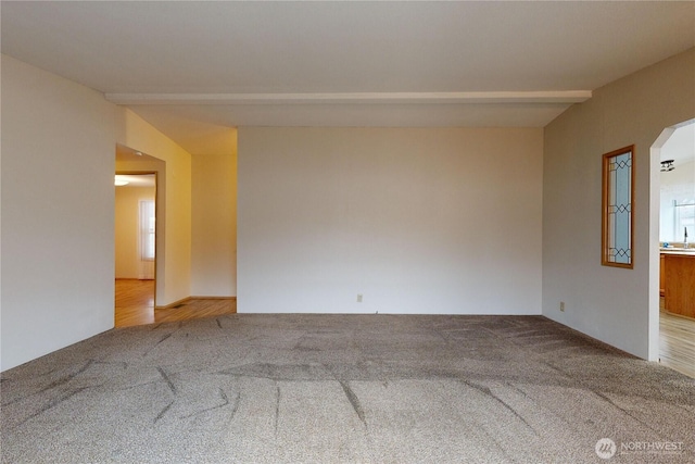 carpeted spare room with beam ceiling