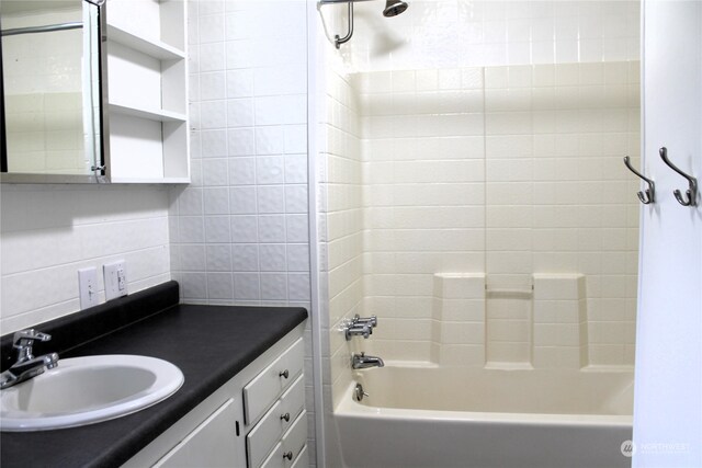 bathroom with tile walls, vanity, decorative backsplash, and bathing tub / shower combination