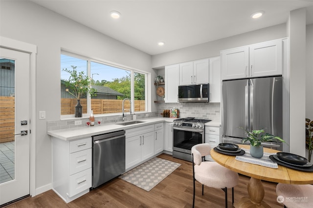 kitchen with sink, backsplash, white cabinetry, stainless steel appliances, and dark hardwood / wood-style flooring