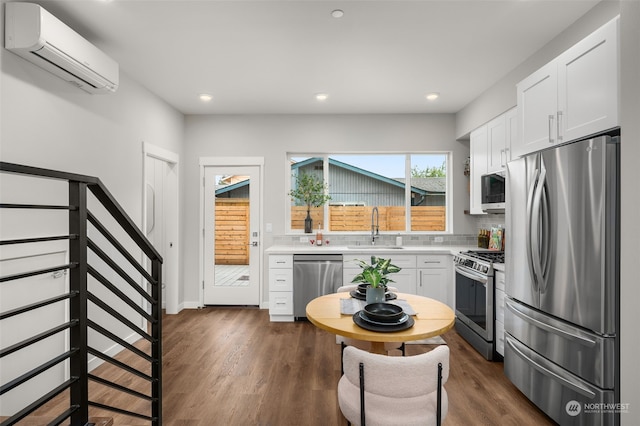 kitchen with white cabinetry, a wall mounted air conditioner, stainless steel appliances, dark hardwood / wood-style floors, and sink