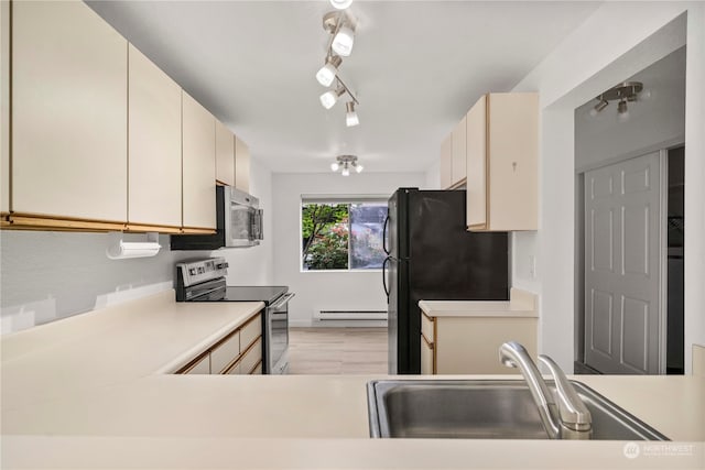 kitchen with sink, light hardwood / wood-style flooring, stainless steel appliances, baseboard heating, and cream cabinets