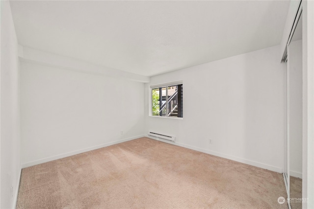 carpeted spare room with a baseboard heating unit