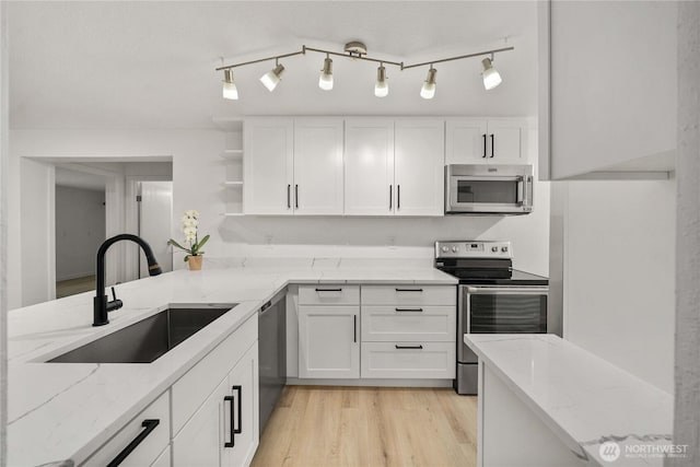 kitchen with light stone counters, appliances with stainless steel finishes, and a sink