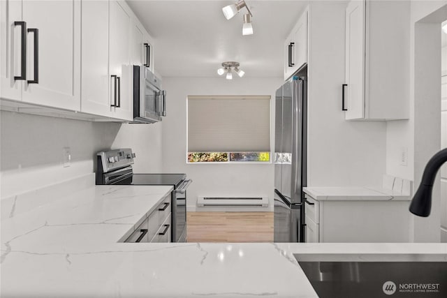 kitchen featuring white cabinets, a baseboard heating unit, appliances with stainless steel finishes, and light stone counters