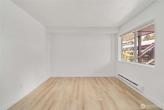spare room featuring wood finished floors, baseboard heating, and baseboards