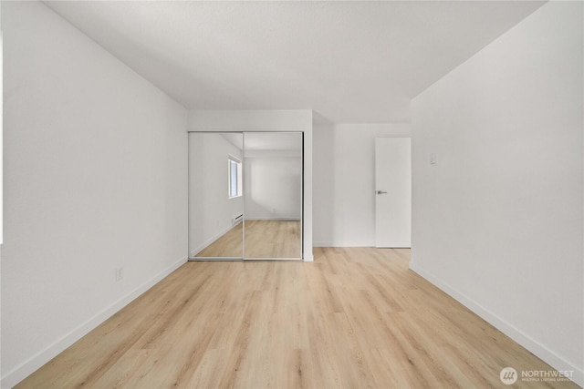 unfurnished bedroom featuring a closet, wood finished floors, and baseboards
