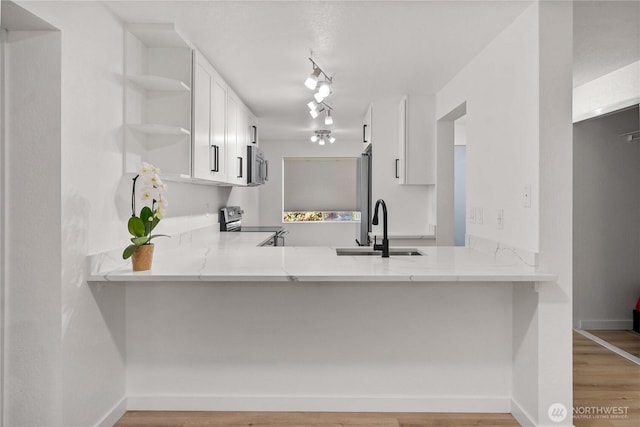 kitchen with appliances with stainless steel finishes, a peninsula, open shelves, and a sink